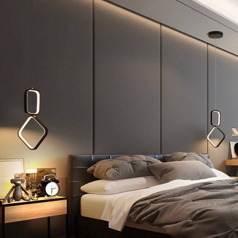 "Pair of geometric pendant lights with metal frames and acrylic diffusers, hanging on either side of a bed in a modern bedroom."