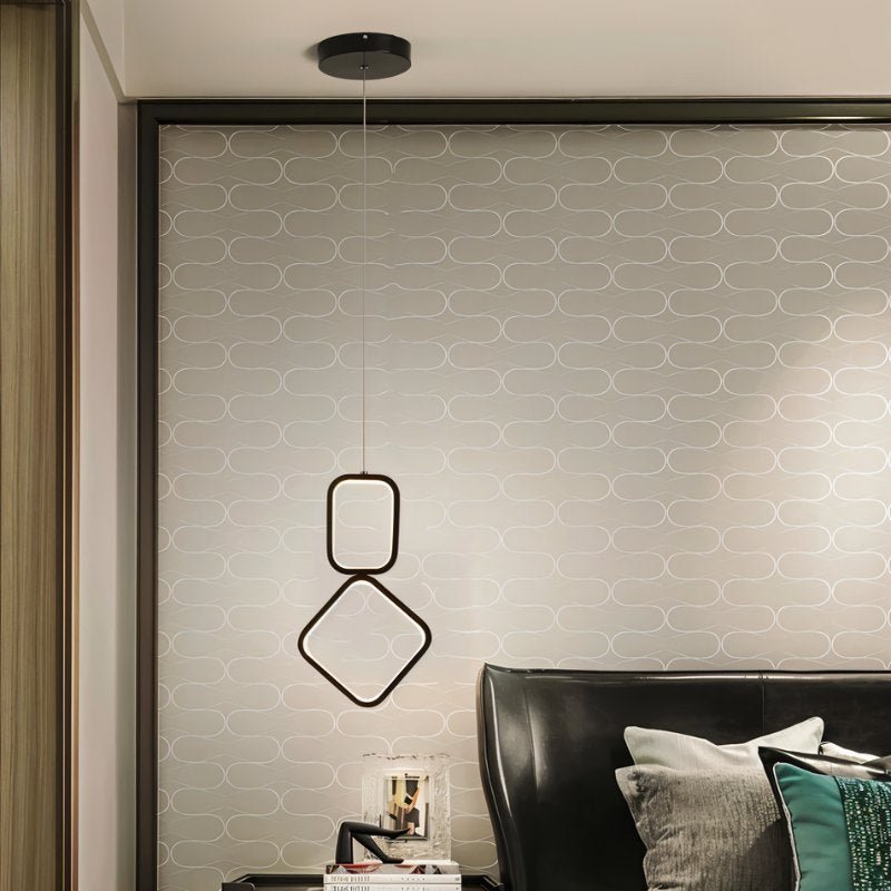 "Single geometric pendant light with metal frame and acrylic diffusers, hanging above a bedside table."