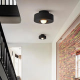 "Two black circular flush mount ceiling lights in a hallway."