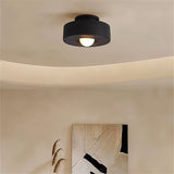 "Black circular flush mount ceiling light in a room with artwork."