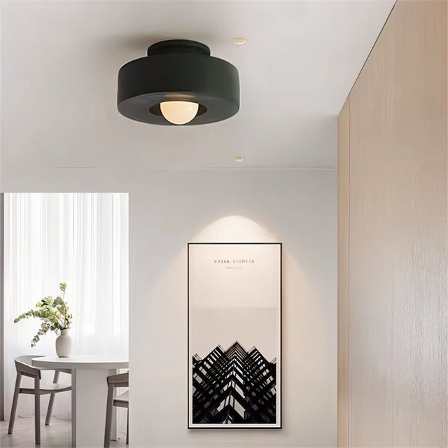 "Green circular flush mount ceiling light in a room with artwork."