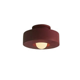 "Red circular flush mount ceiling light with recessed bulb."
