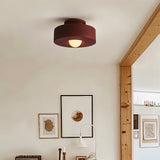 "Red circular flush mount ceiling light in a room with framed art."