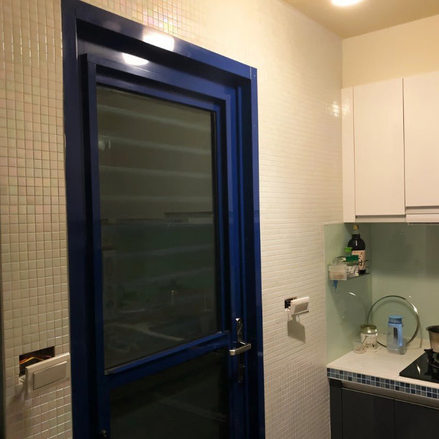 Kacakar Mosaic Tiles installed on a kitchen wall near a blue door, offering a sleek and glossy wall panel surface.