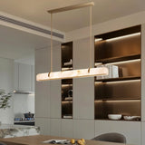 "Modern alabaster and copper linear chandelier illuminating a contemporary kitchen island."