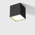 Black cube ceiling downlight with warm white glow on neutral background.