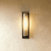 Two vertical black wall sconces with ribbed glass panels flanking modern black-framed glass doors on white wall, lifestyle se