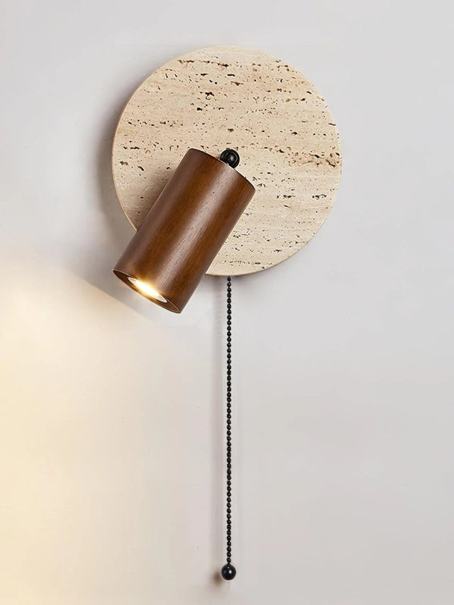 "Close-up of a yellow travertine round wall lamp with wooden cylindrical shade and pull chain, modern bedside light."