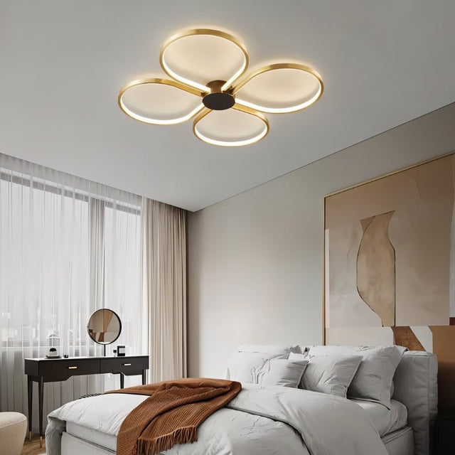 "Modern ceiling light with four circular LED rings illuminating a contemporary bedroom with a warm, balanced glow."