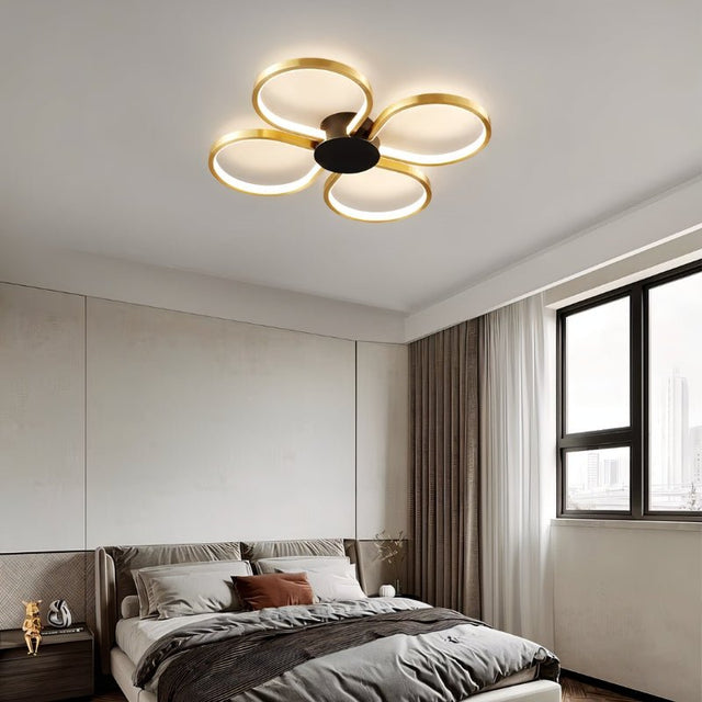 "Modern ceiling light with four circular LED rings in a clover design, illuminating a contemporary bedroom."