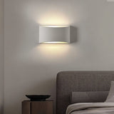 "Modern curved rectangular gypsum wall lamp casting soft light upward and downward in a contemporary bedroom."