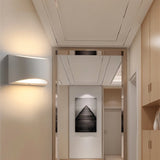 "Modern curved rectangular gypsum wall lamp providing ambient up and down lighting in a contemporary hallway."