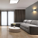 "Modern curved rectangular gypsum wall lamp providing ambient up and down lighting in a contemporary living room with a sofa."