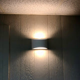 "Modern curved rectangular gypsum wall lamp casting soft light upward and downward on a textured wall."