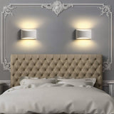 "Pair of modern curved rectangular gypsum wall lamps symmetrically placed above a tufted headboard in a contemporary bedroom, casting soft ambient light."