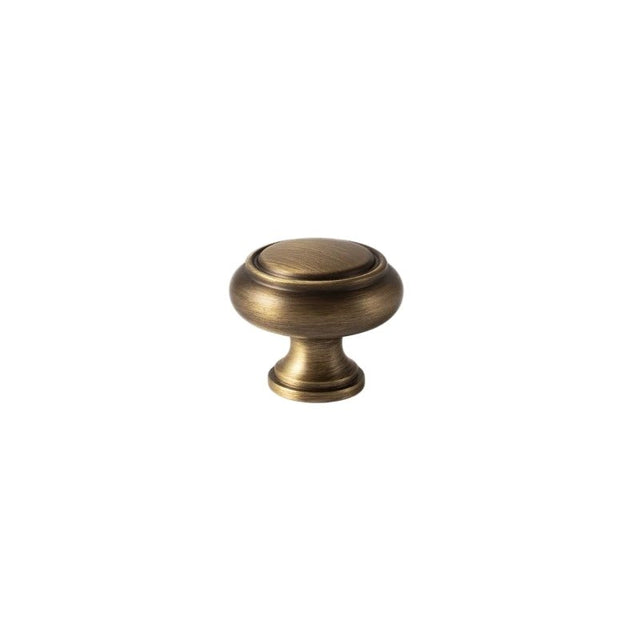 "An antique brass cabinet knob with a classic, elegant design, isolated on a white background."