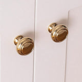 "Polished gold brass knobs on a cabinet, showcasing an elegant, timeless design for luxury interiors."
