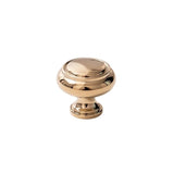 "A polished gold brass cabinet knob with a classic, elegant design, isolated on a white background."