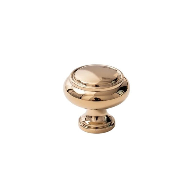 "A polished gold brass cabinet knob with a classic, elegant design, isolated on a white background."
