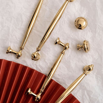 "Luxury polished gold brass knobs and pull bars with intricate detailing, ideal for classic and transitional interiors."