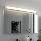 "White modern wall lamp illuminating a bathroom mirror with a picture frame and toiletries reflected."