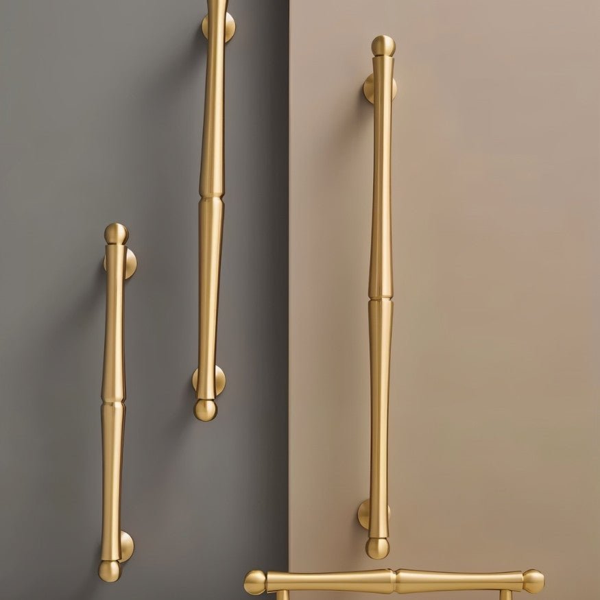 "Several brass pull bar handles of varying sizes mounted on cabinet doors."