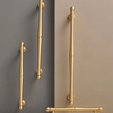 "Several brass pull bar handles of varying sizes mounted on cabinet doors."