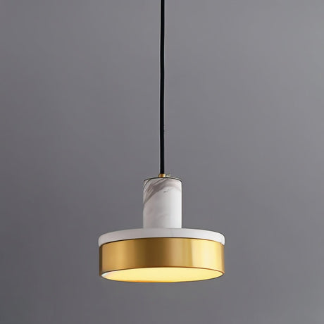 "A modern pendant light with white marble and brass accents hangs from a gray background, emitting a soft, warm glow."