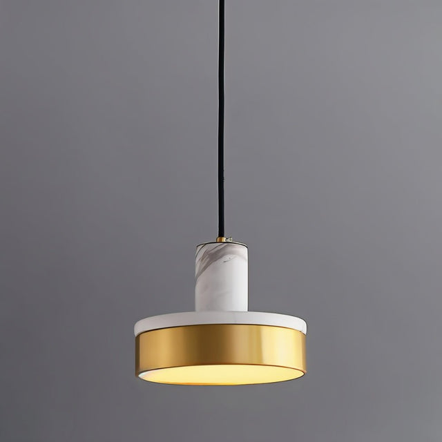 "A modern pendant light with white marble and brass accents hangs from a gray background, emitting a soft, warm glow."