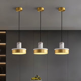 "Three pendant lights with white marble and brass accents hang in a modern space, providing a soft, ambient glow."