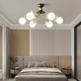 "Multi-light ceiling fixture with glass globes and petal details illuminating a modern bedroom with a bed and nightstands."