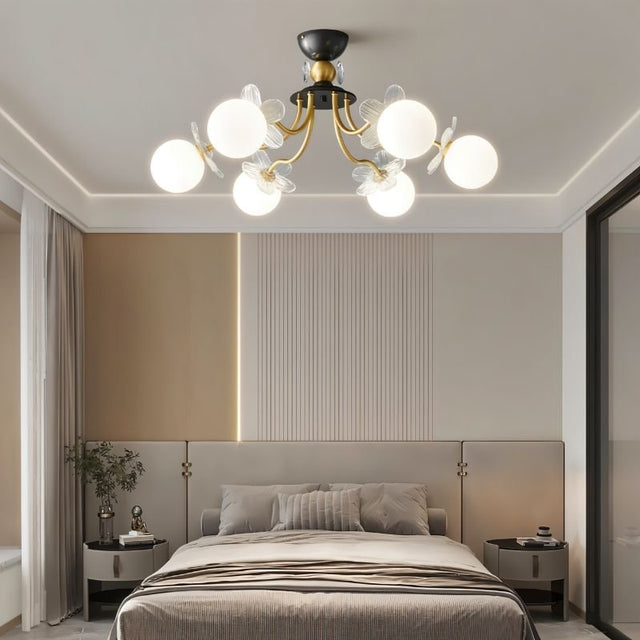 "Multi-light ceiling fixture with glass globes and petal details illuminating a modern bedroom with a bed and nightstands."