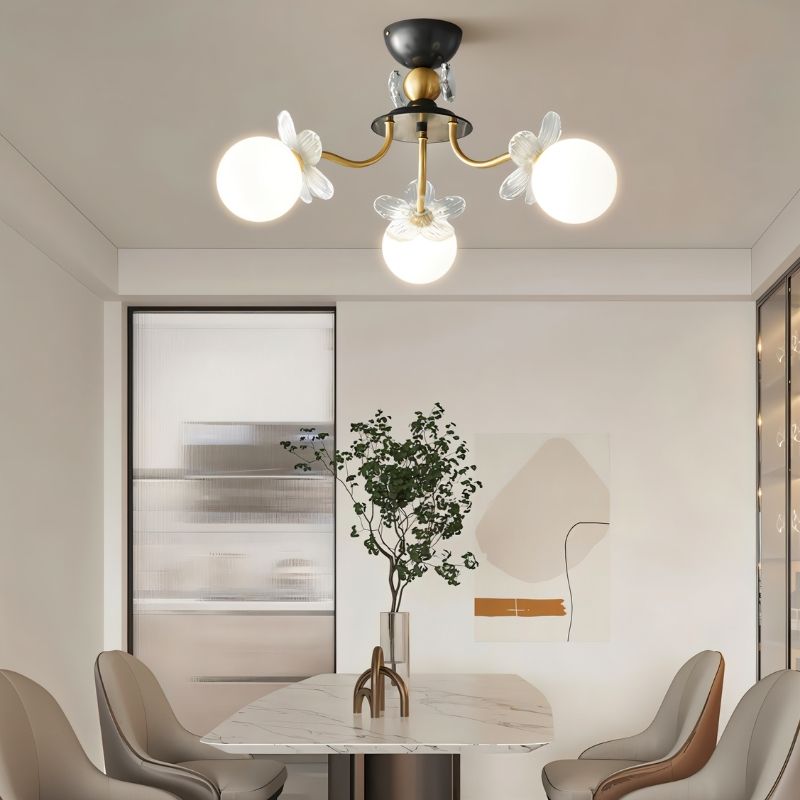 "Multi-light ceiling fixture with glass globes and petal details illuminating a modern dining room with a table and chairs."