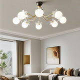 "Multi-light ceiling fixture with glass globes and petal details illuminating a modern living room with a sofa and artwork."