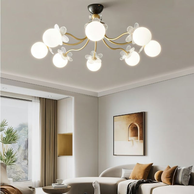 "Multi-light ceiling fixture with glass globes and petal details illuminating a modern living room with a sofa and artwork."