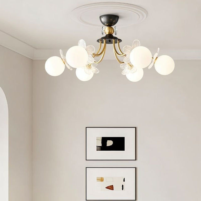 "Multi-light ceiling fixture with glass globes and petal details above two framed art pieces in a modern interior."