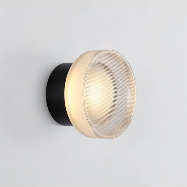 "A modern, minimalist wall lamp with a circular glass diffuser and a sleek black frame, emitting a soft, ambient glow."