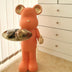 Red bear figurine with gold accents holding a serving tray in a minimalist bedroom setting.