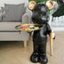 Black marble bear figurine with gold accents holding a brass tray, displayed in a modern living room setting.