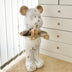 White ceramic bear figurine with gold accents holding a tray, standing indoors near a dresser.