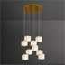 Cylindrical pendant chandelier with ten frosted white glass cube shades suspended from brass canopy against gray wall.