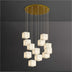 Multi-pendant chandelier with alabaster cube shades and brass canopy suspended against a gray wall.