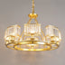 Gold brass chandelier with crystal prism shades arranged in a circular design against a neutral background.