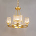 Gold chandelier with three crystal glass shades hanging against a neutral gray background.