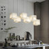 Clustered alabaster pendant lights with warm glow suspended above a modern desk with decorative accessories.