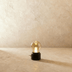 Gold brass globe pendant light with clear glass dome, displayed in studio setting with vintage camera and white pebbles.