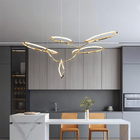 "A modern chandelier with interconnecting brass loops and acrylic diffusers hangs in a contemporary kitchen with gray cabinets."
