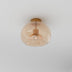 Amber glass dome ceiling light with brass fixture mounted on white ceiling.