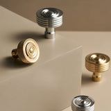 "Group of brass knobs with concentric ring designs and ridged surfaces in various metallic finishes."