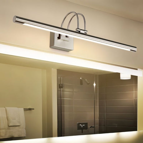 "A silver wall lamp with a linear LED bar and dual-arch mounting, illuminating a bathroom vanity mirror and reflecting a shower stall."